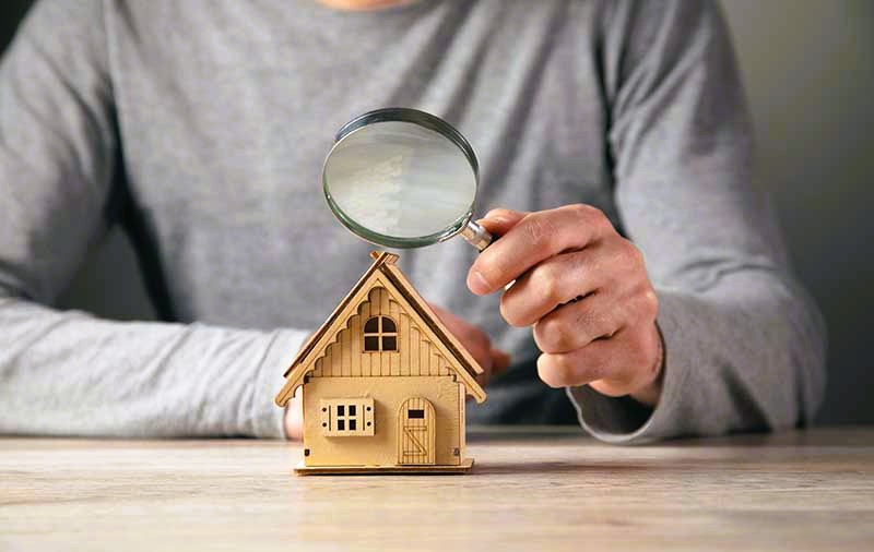 man hold magnifying glass looking house